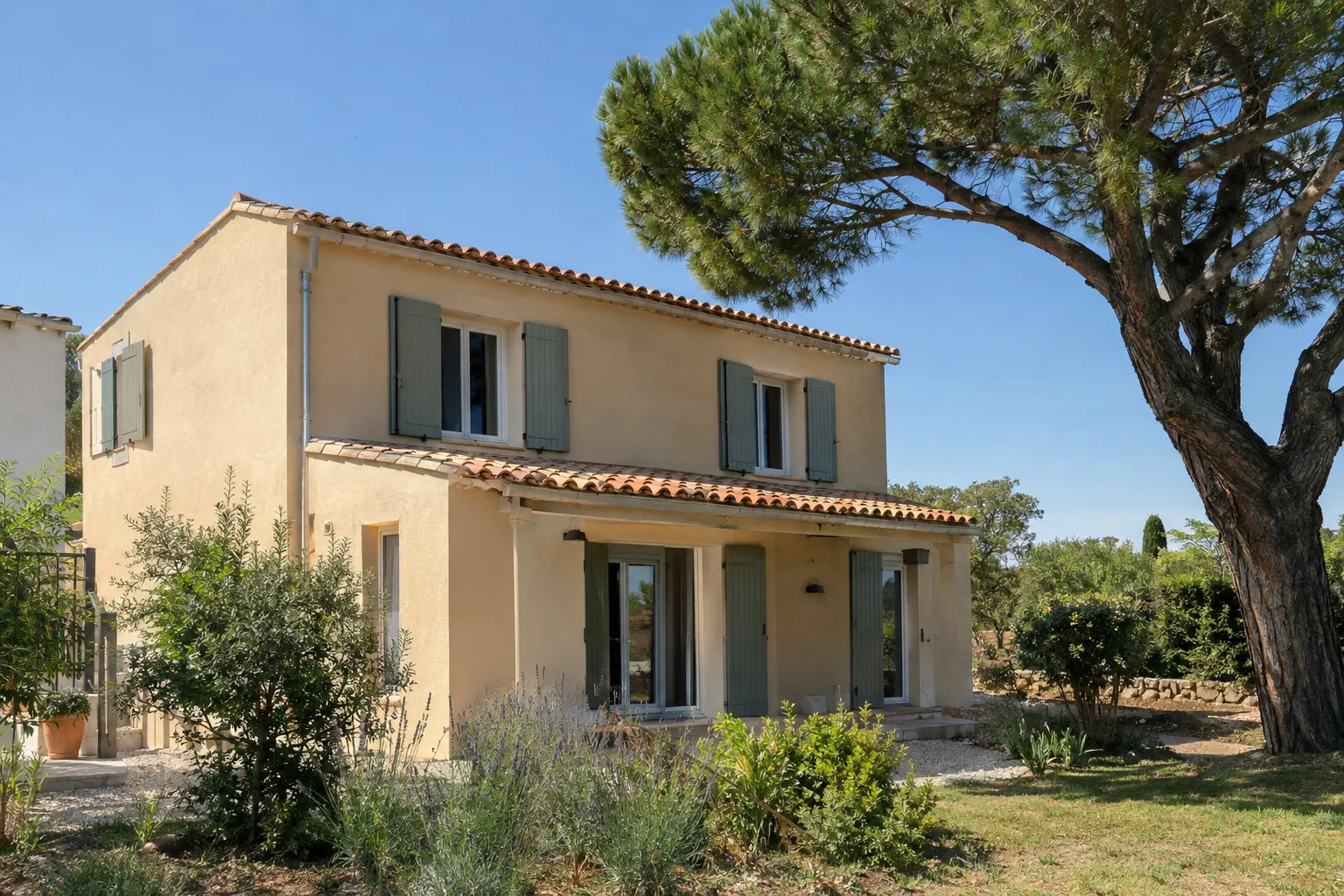 Une maison provençale après ravalement de façade, enduit ocre clair, volets neufs et pin parasol.